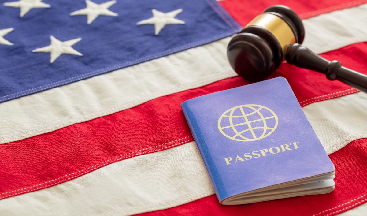 Blue passport and judge gavel on USA flag background, closeup view. Immigration, United States of America visa concept